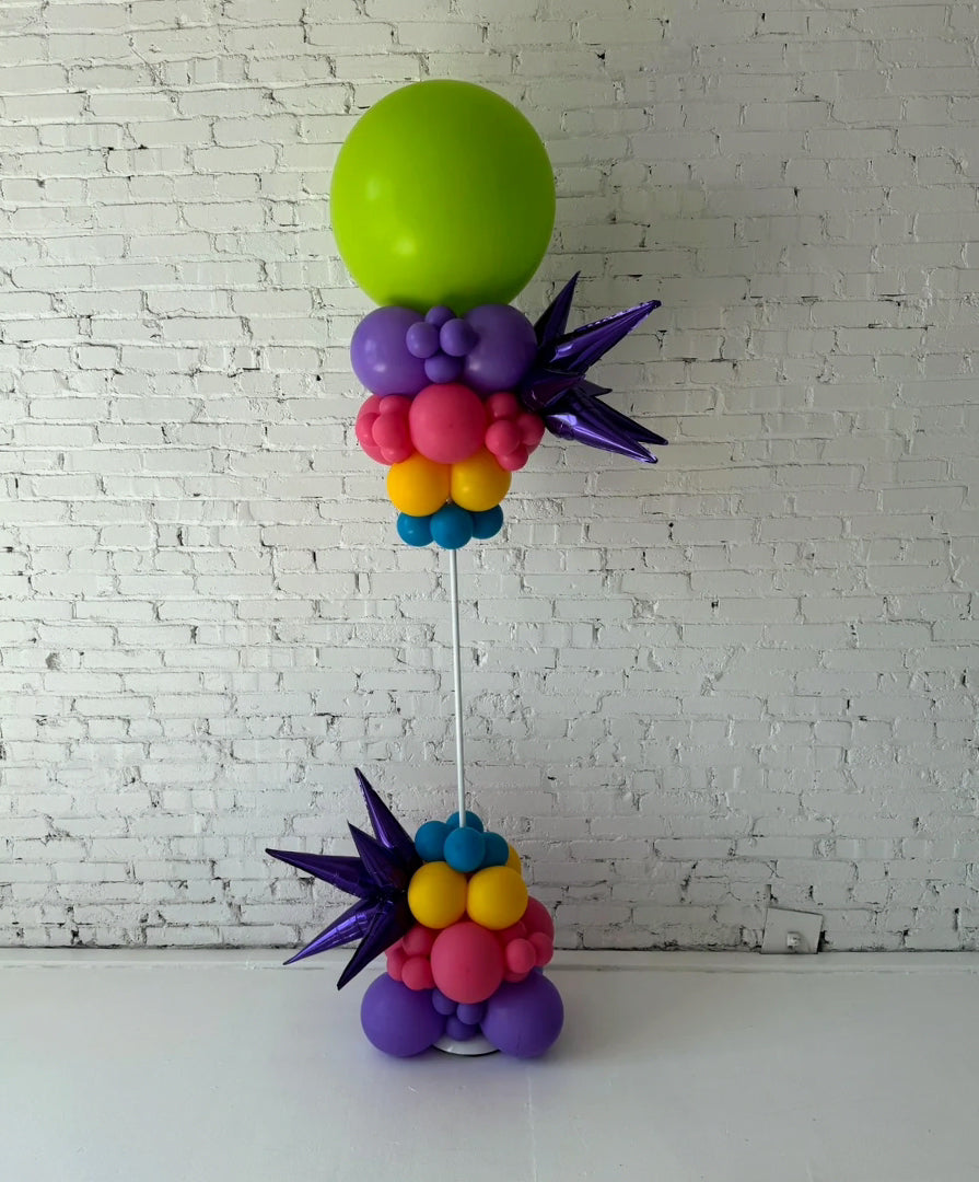 Freeform balloon column installation by Lady With The Balloons in Leawood, Kansas — featuring vibrant colors, metallic starburst accents, and a modern sculptural design for event décor.